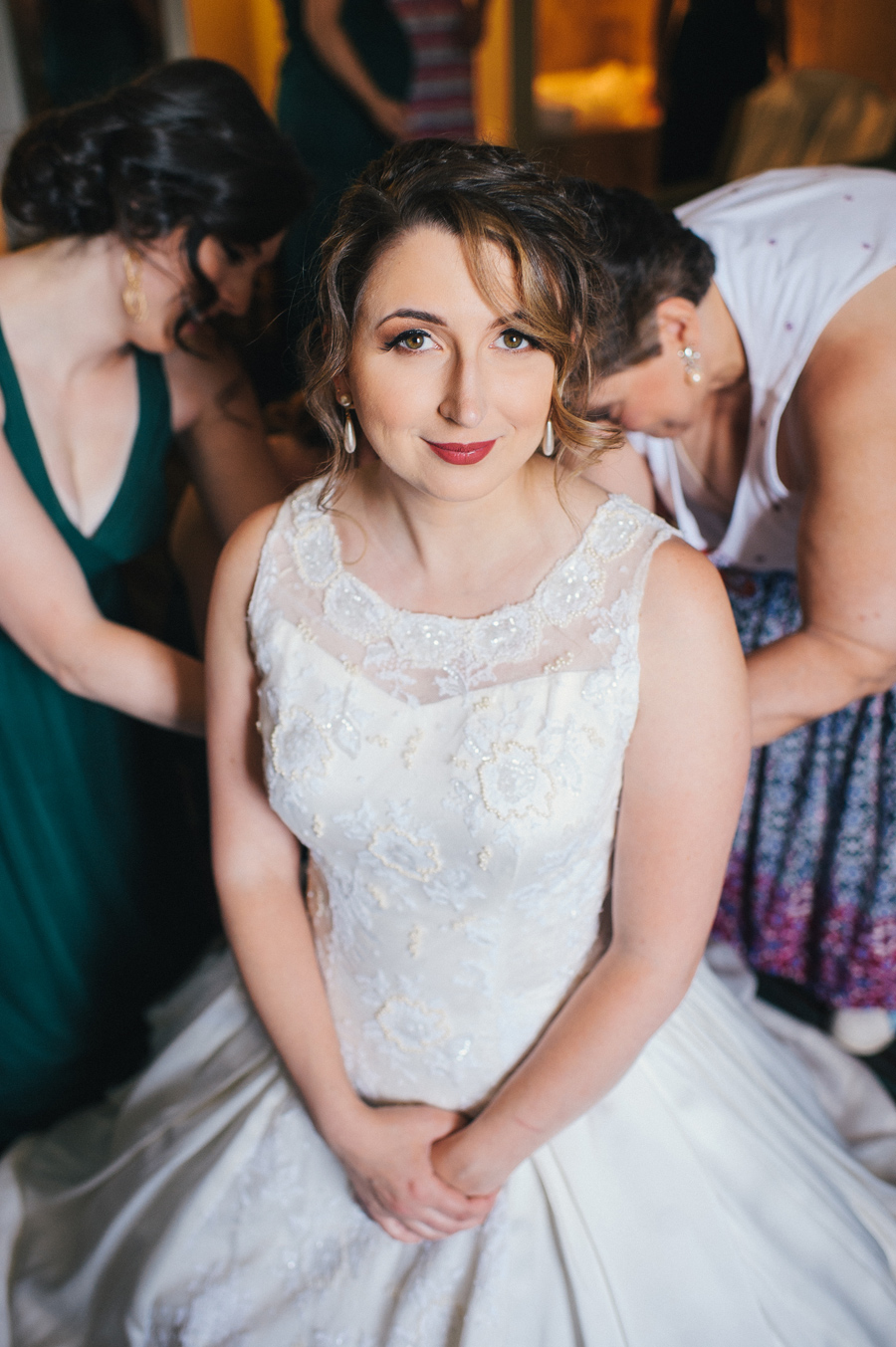 bride having her dress buttoned by bridal party members