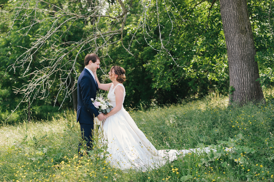 bride and groom gazing at each other in a field