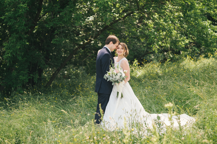 bride and groom posing near a wooded area