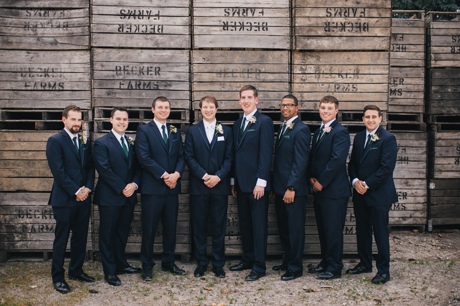 groomsmen lined up in front of becker farms wood palette wall