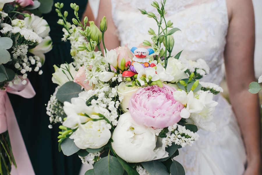 close up of small clown toy resting on bride's bouquet