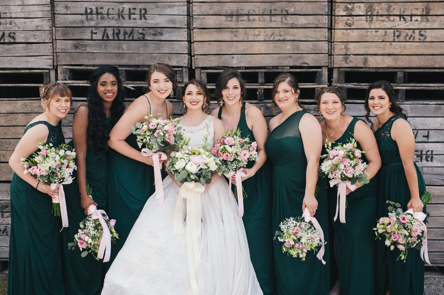 bride and bridesmaids smiling with wooden crates in background