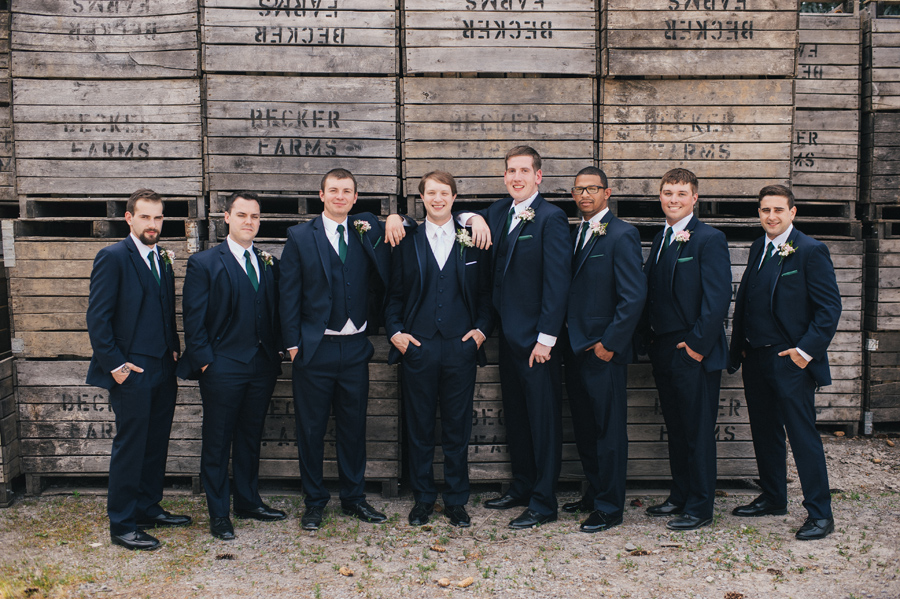 groom and groomsman casually standing in front of wood wall at becker farms