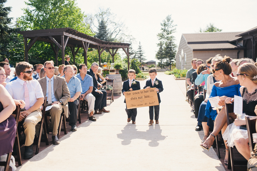 two ring bearers holding a sign together walking down the aisle
