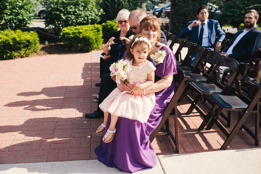 a flower girl sitting on a wedding guest's lap