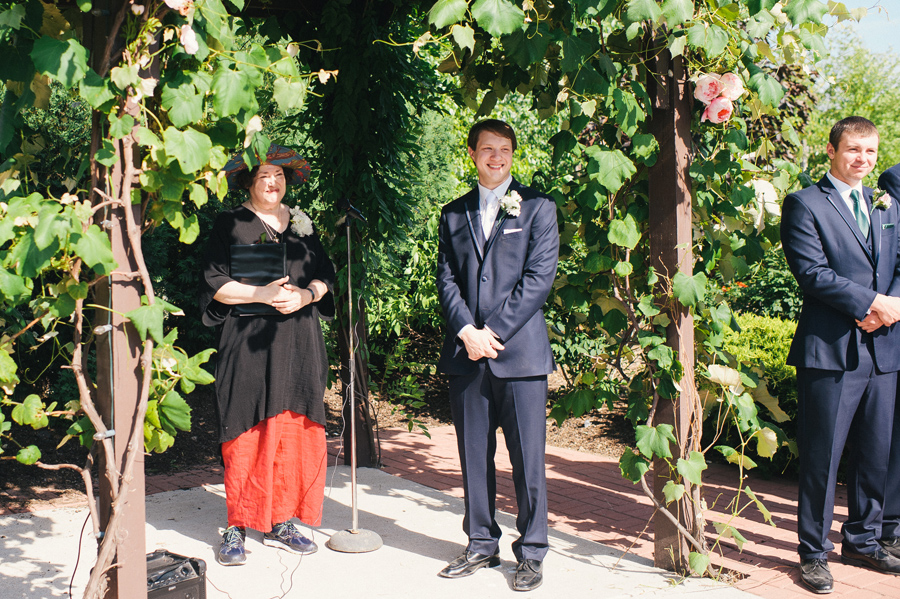 groom awaiting his bride under the grapevine arbor