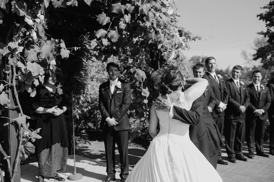 black and white of bride hugging her father at the end of the aisle