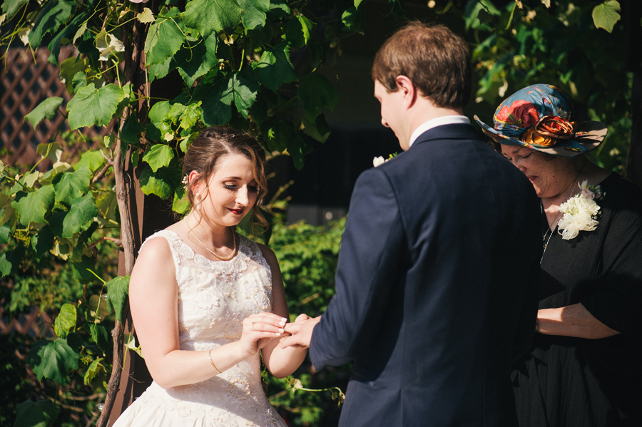 bride placing a wedding band on groom's finger