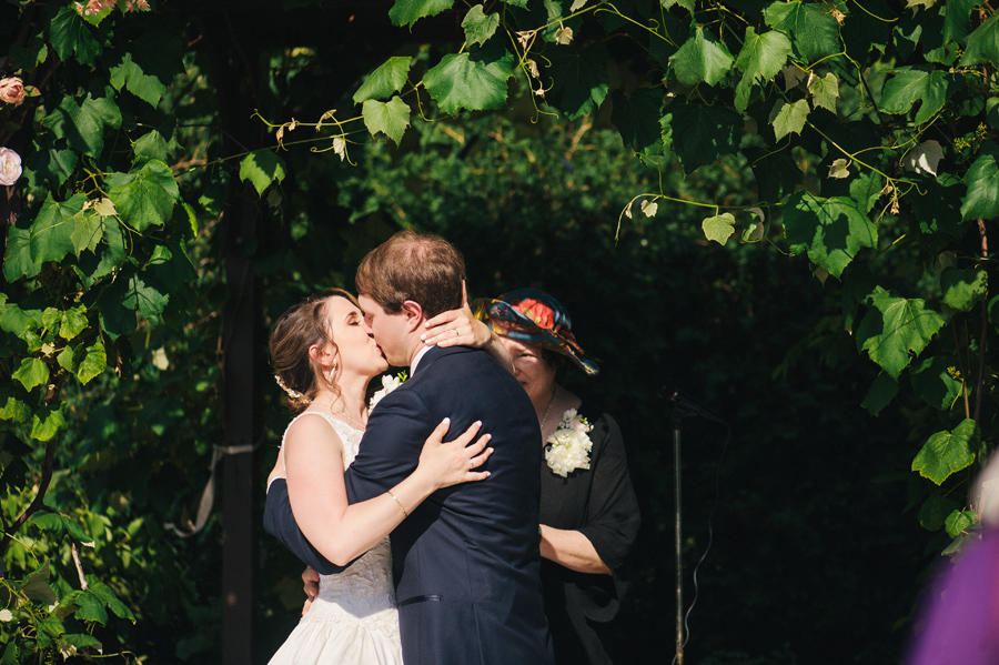 bride and groom kissing under grapevine arbor at becker farms