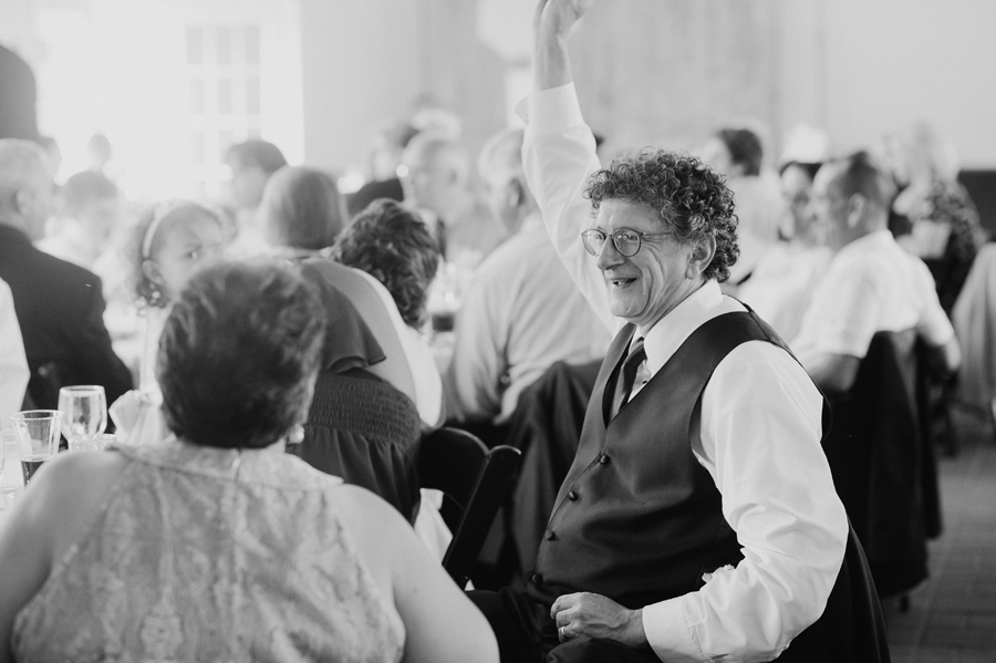 black and white of father of the bride cheering during reception