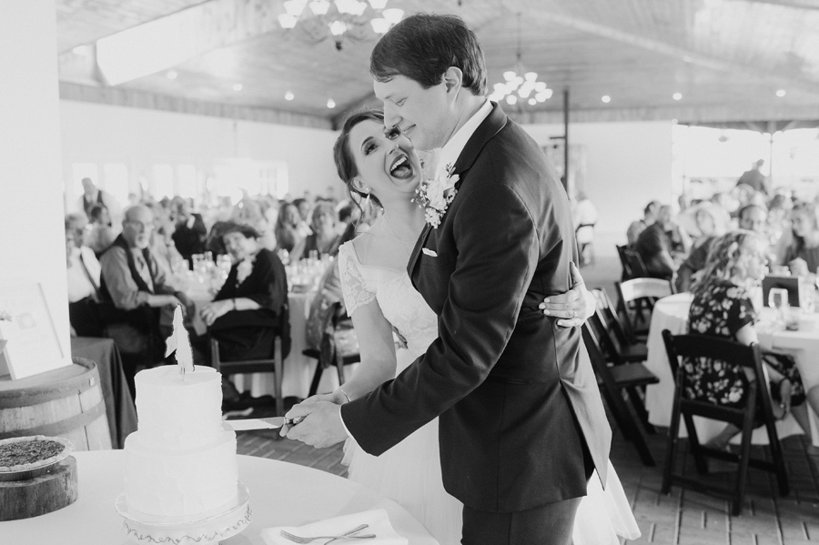 black and white of bride and groom performing cake cutting ceremony