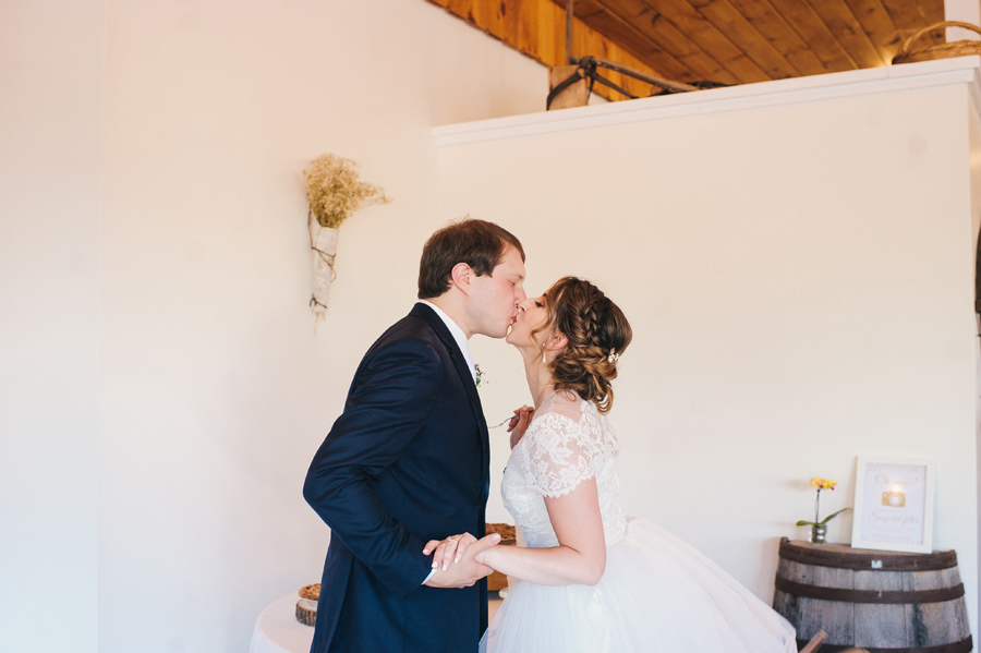 bride and groom kissing after tasting cake together