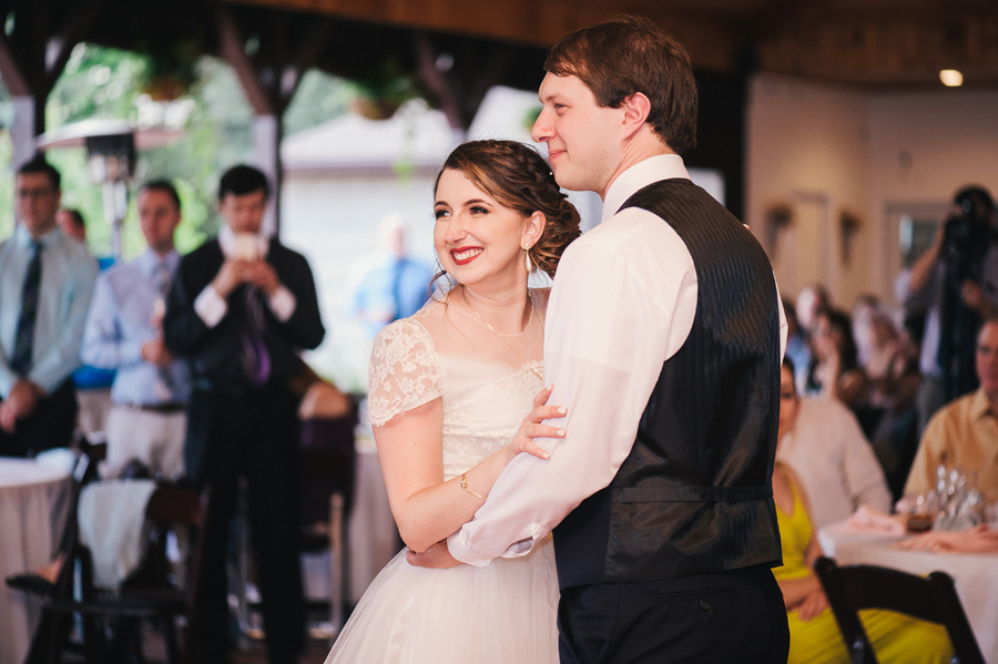 bride and groom smiling at guests during first dance