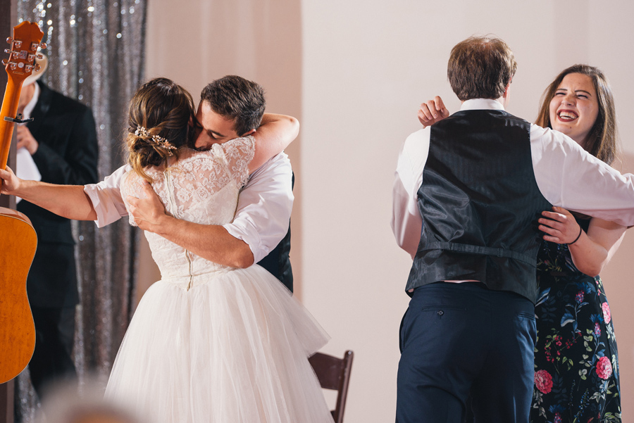 bride and groom hugging reception musicians