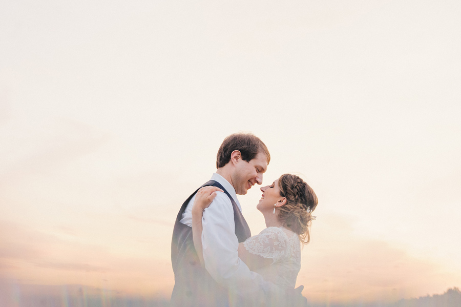 bride and groom holding each other and smiling at sunset