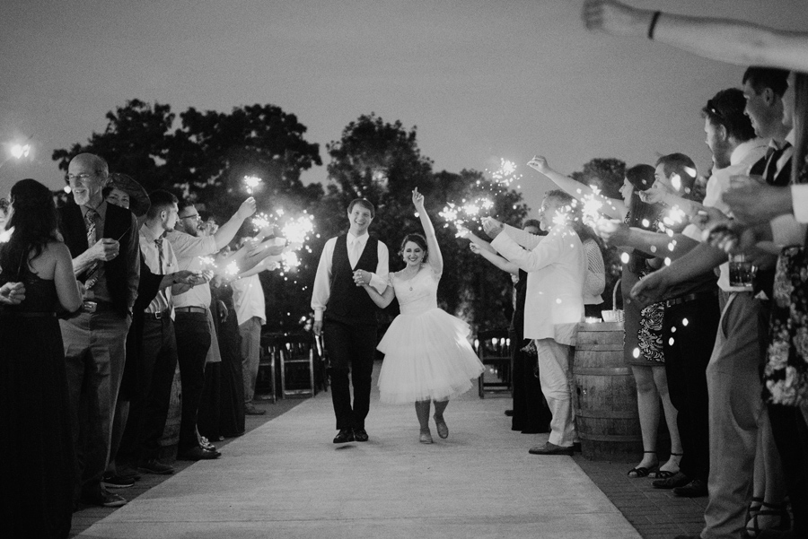 black and white of bride and groom walking through sparkler send off