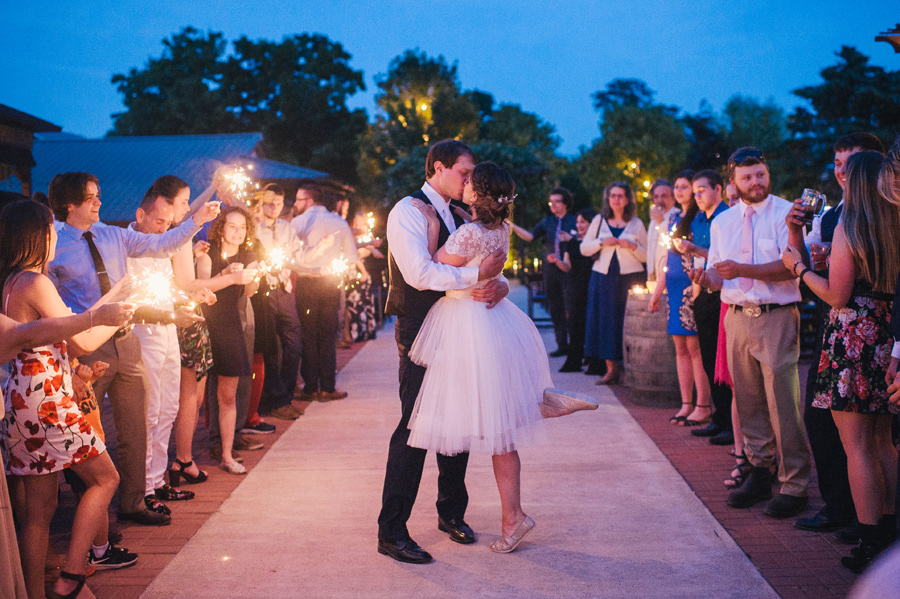 bride and groom kissing during sparkler send off at night