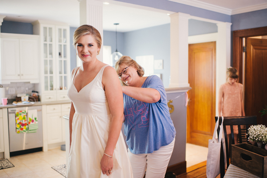 mother of the bride buttoning bride's dress