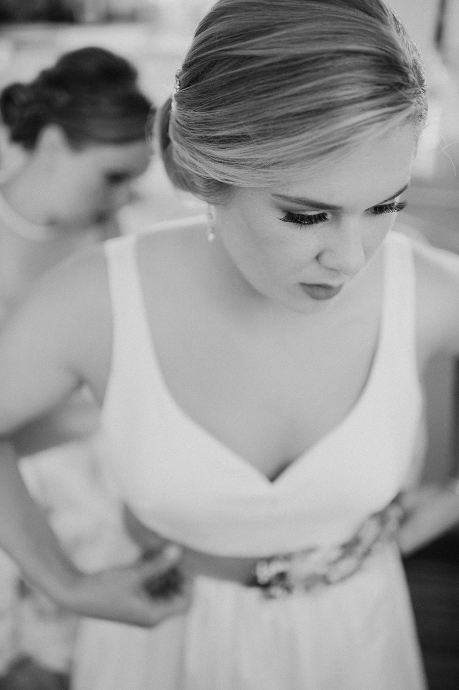 black and white photo of bride's dress being put on