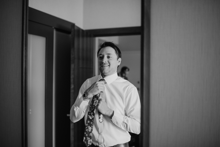 black and white photo groom adjusting his tie