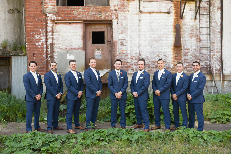 groomsmen lined up in front of brick wall