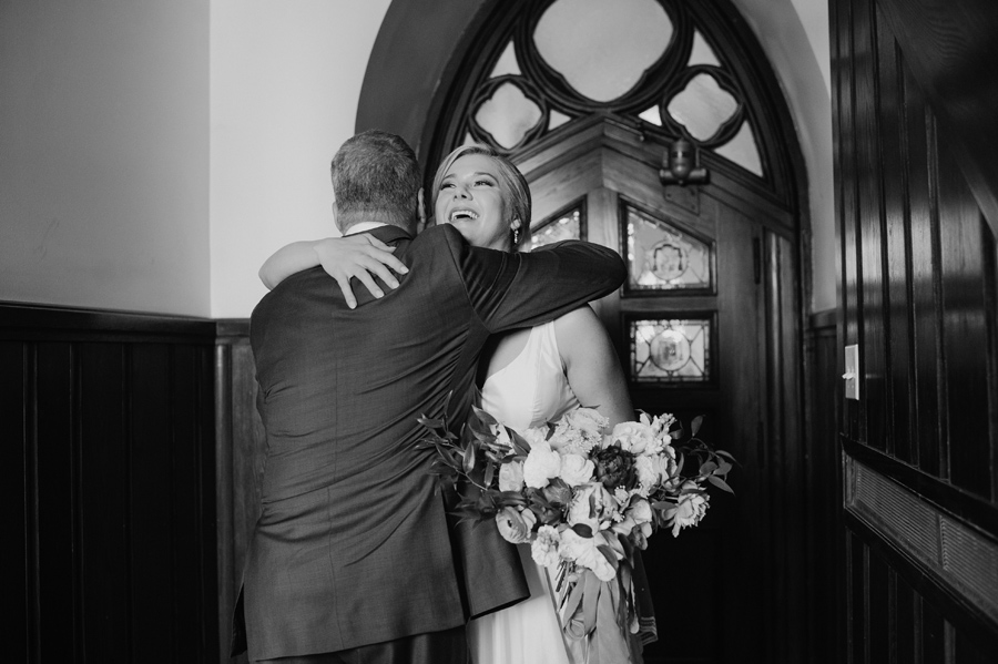 black and white of bride hugging her father inside the church