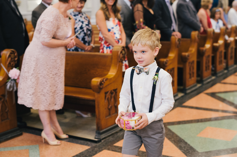 ring bearer wearing floral print bow tie walking down the aisle