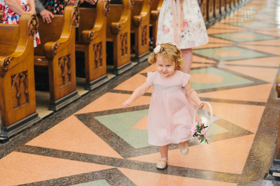 flower girl holding decorative flower ring walking down the aisle