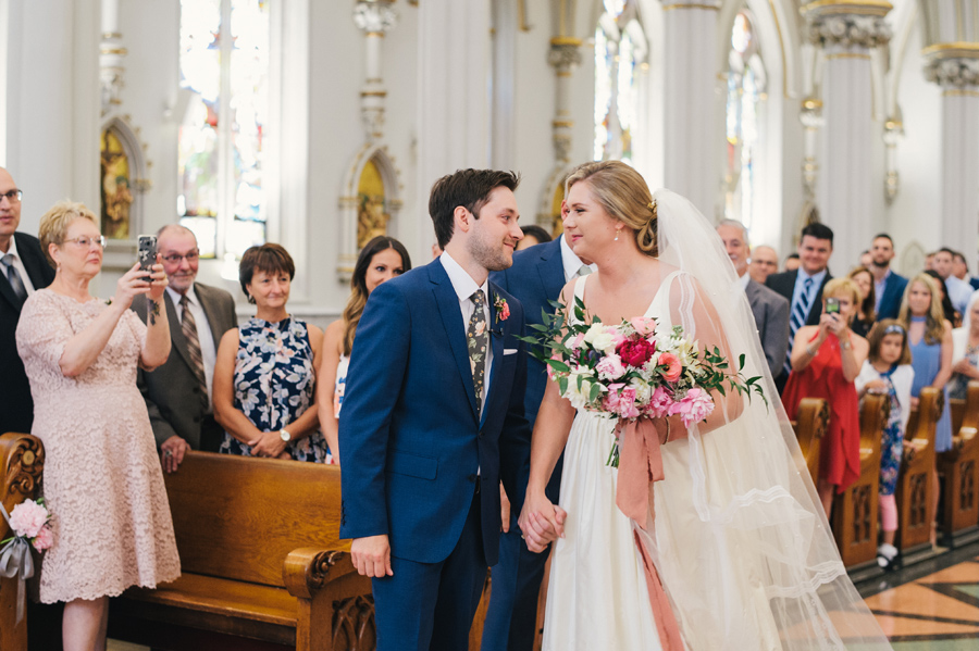 groom and bride happily looking at each other at the top of the aisle