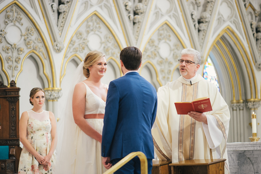 bride and groom facing each other as priest speaks