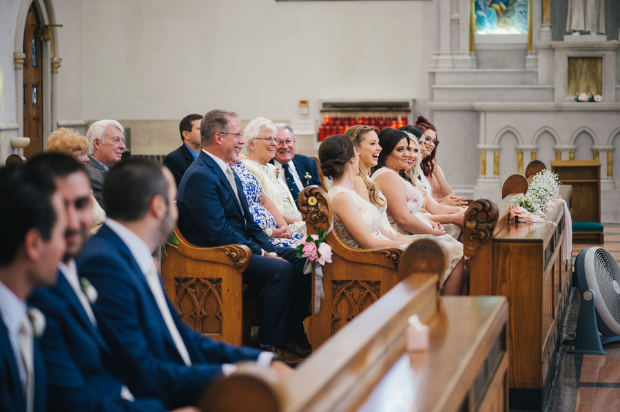 wedding guests and bridal party laughing in the pews