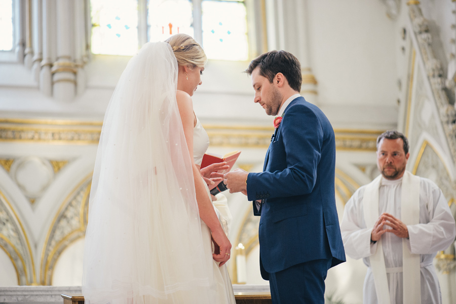 groom placing wedding band on bride's finger