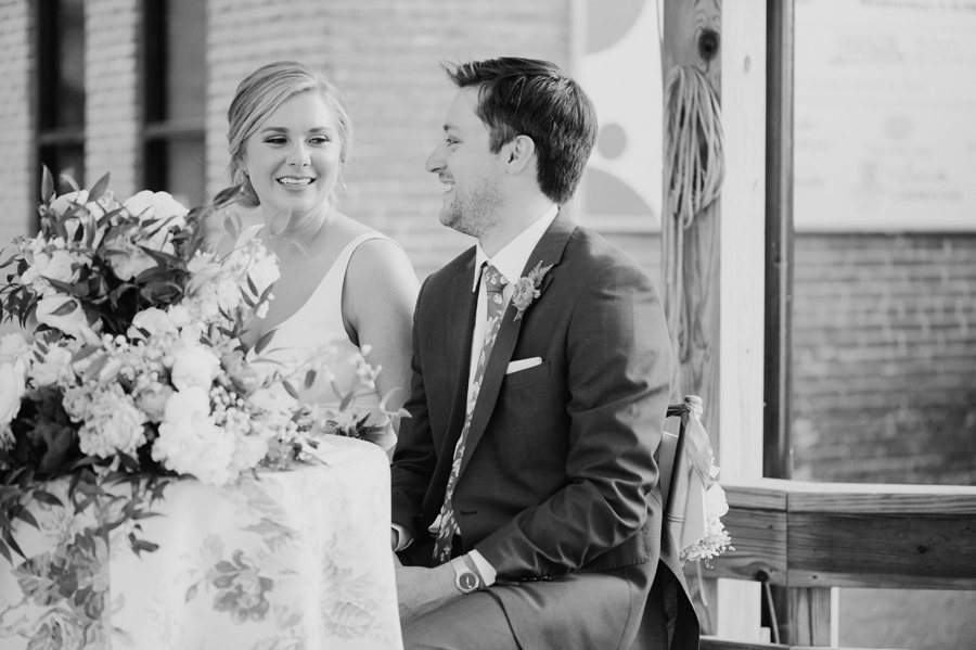 black and white photo of bride and groom smiling during speeches