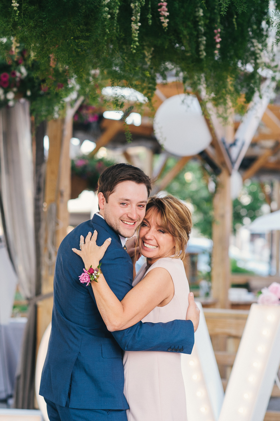 groom and his mother smiling at the camera during mother son dance