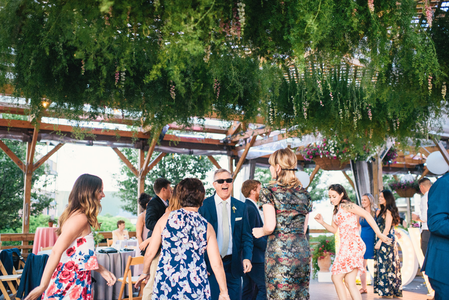 wedding guests dancing under greenery chandelier made by west wind floral