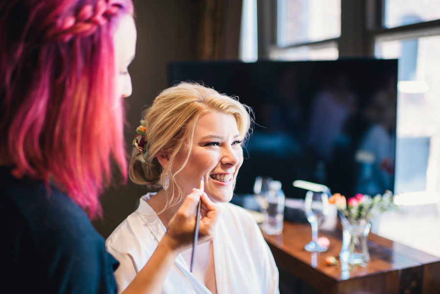 bride smiling while getting her makeup done by rachel rizzo