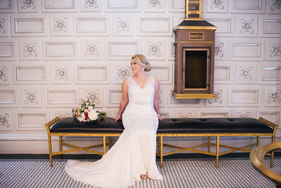 bride posing on a bench in the lobby of the curtiss hotel