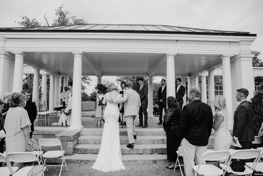 black and white of father of the bride helping her up the steps at the ceremony