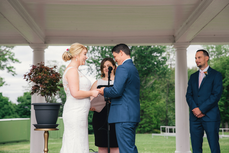 bride and groom exchanging rings at delaware park rose garden