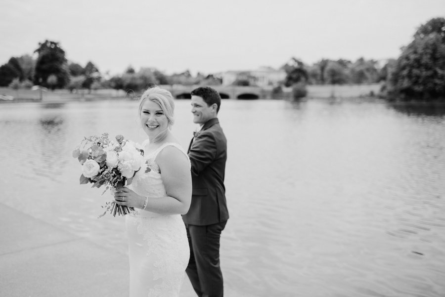 black and white of bride smiling at the camera with groom