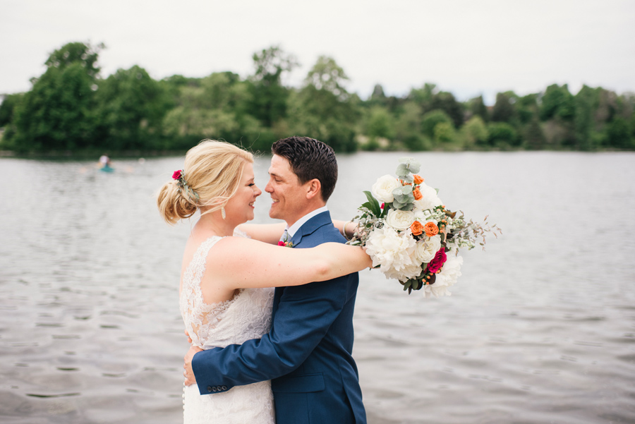 bride and groom smiling at each other in front of hoyt lake