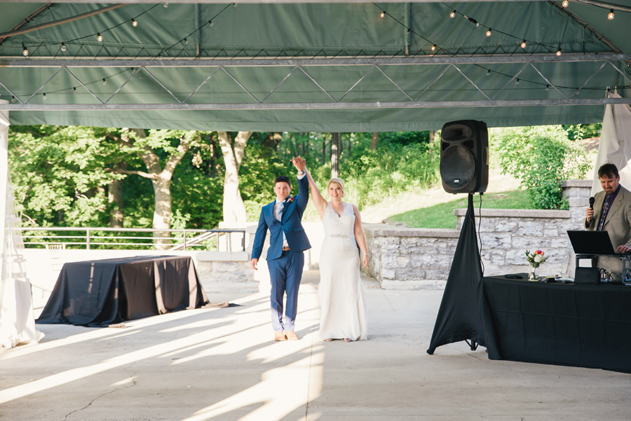 bride and groom enter outdoor tented patio for first dance