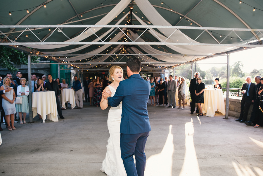 bride and groom dancing together under tent