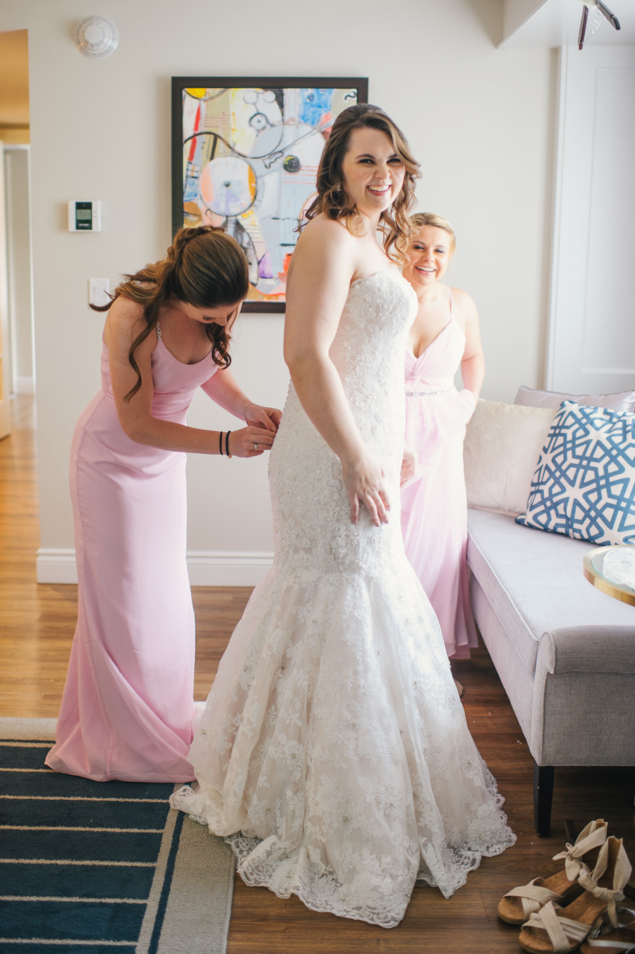 bridesmaid buttoning the bride into her dress