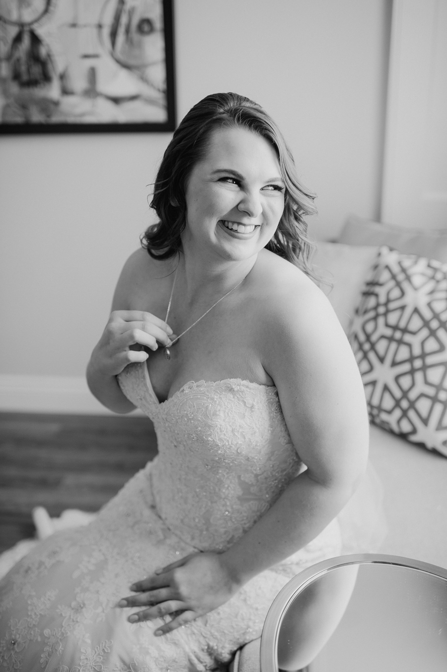 black and white photo of the bride smiling and holding the locket around her neck