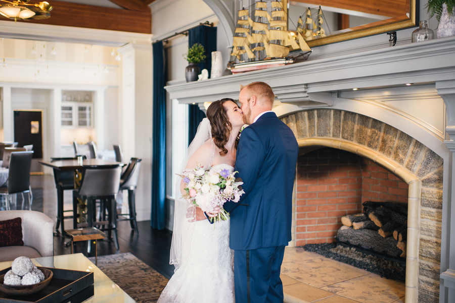 bride and groom kissing in front of fireplace mantel