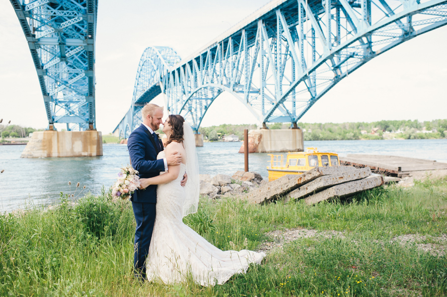 bride and groom facing each other underneath the grand island bridge