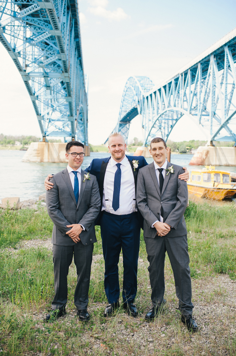 groom and groomsmen posing under the grand island bridge