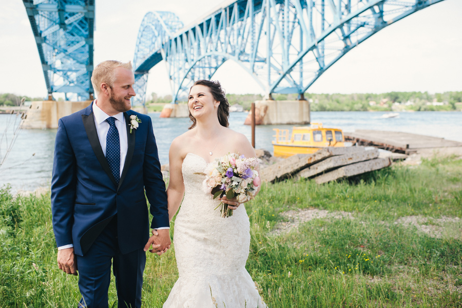 bride and groom holding hands by the water