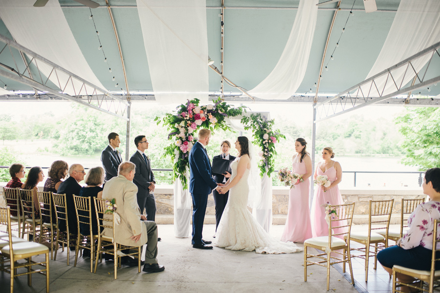bride and groom standing together under the floral arbor by wild blossom hollow